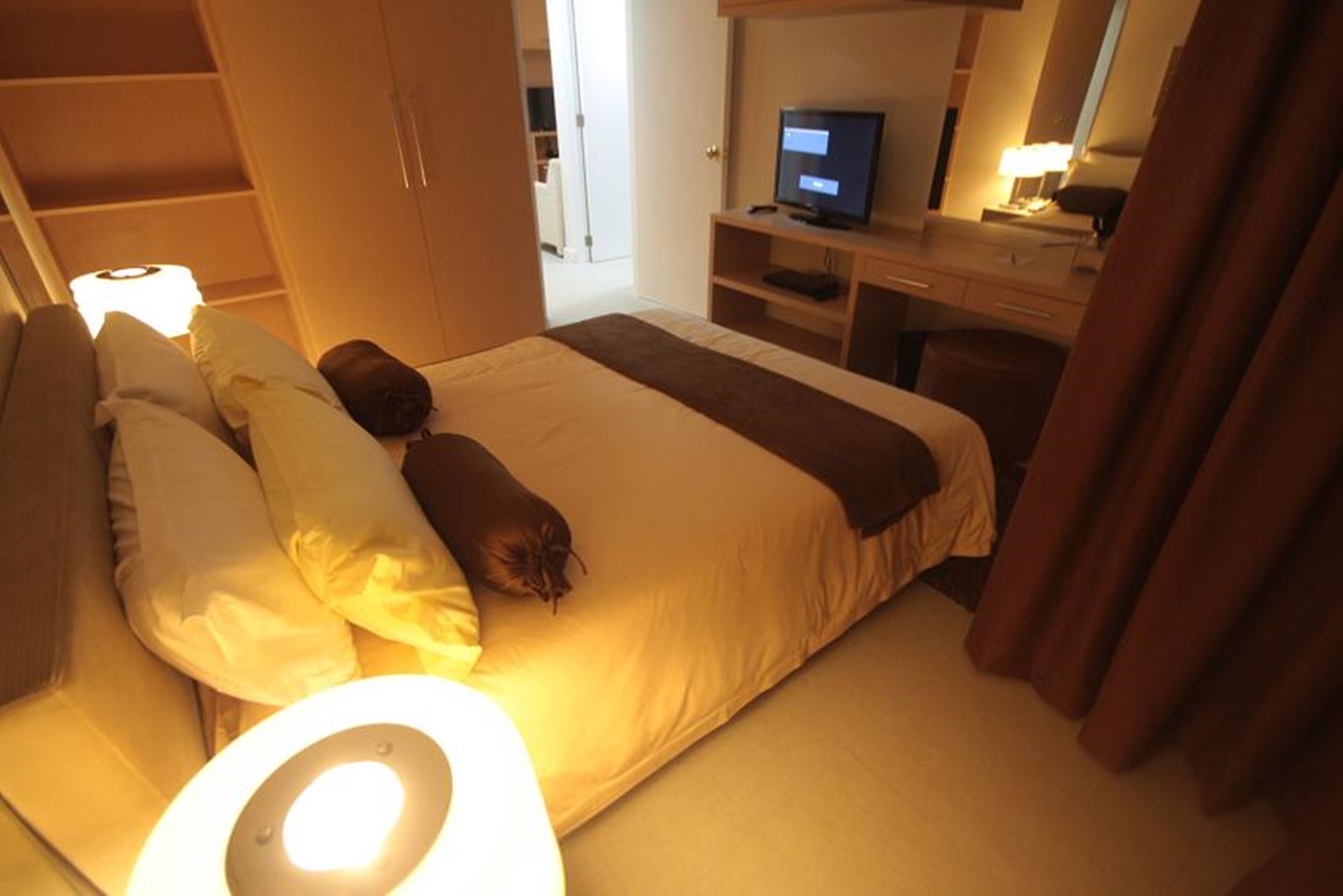 Una habitación de hotel con una cama, un escritorio con computadora y televisión.