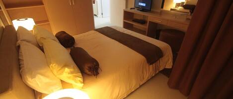 Una habitación de hotel con una cama, un escritorio con computadora y televisión.