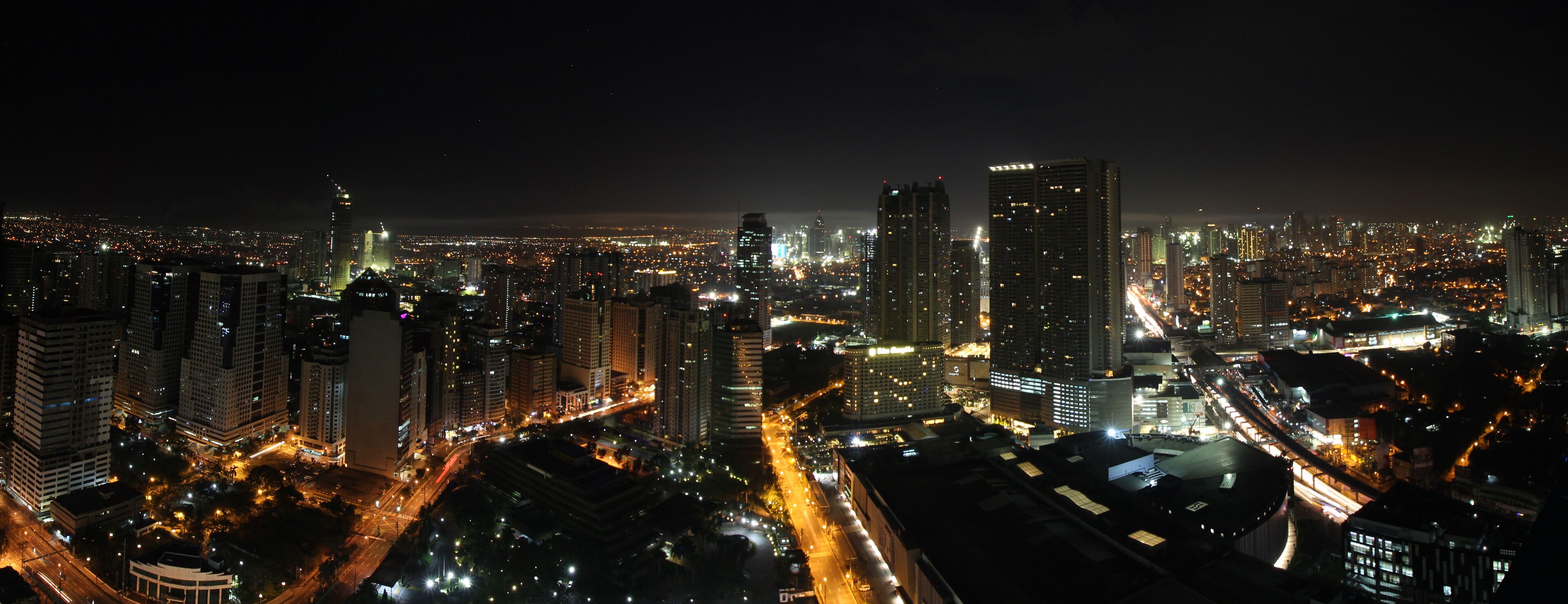A nighttime cityscape with high-rise buildings and illuminated streets.