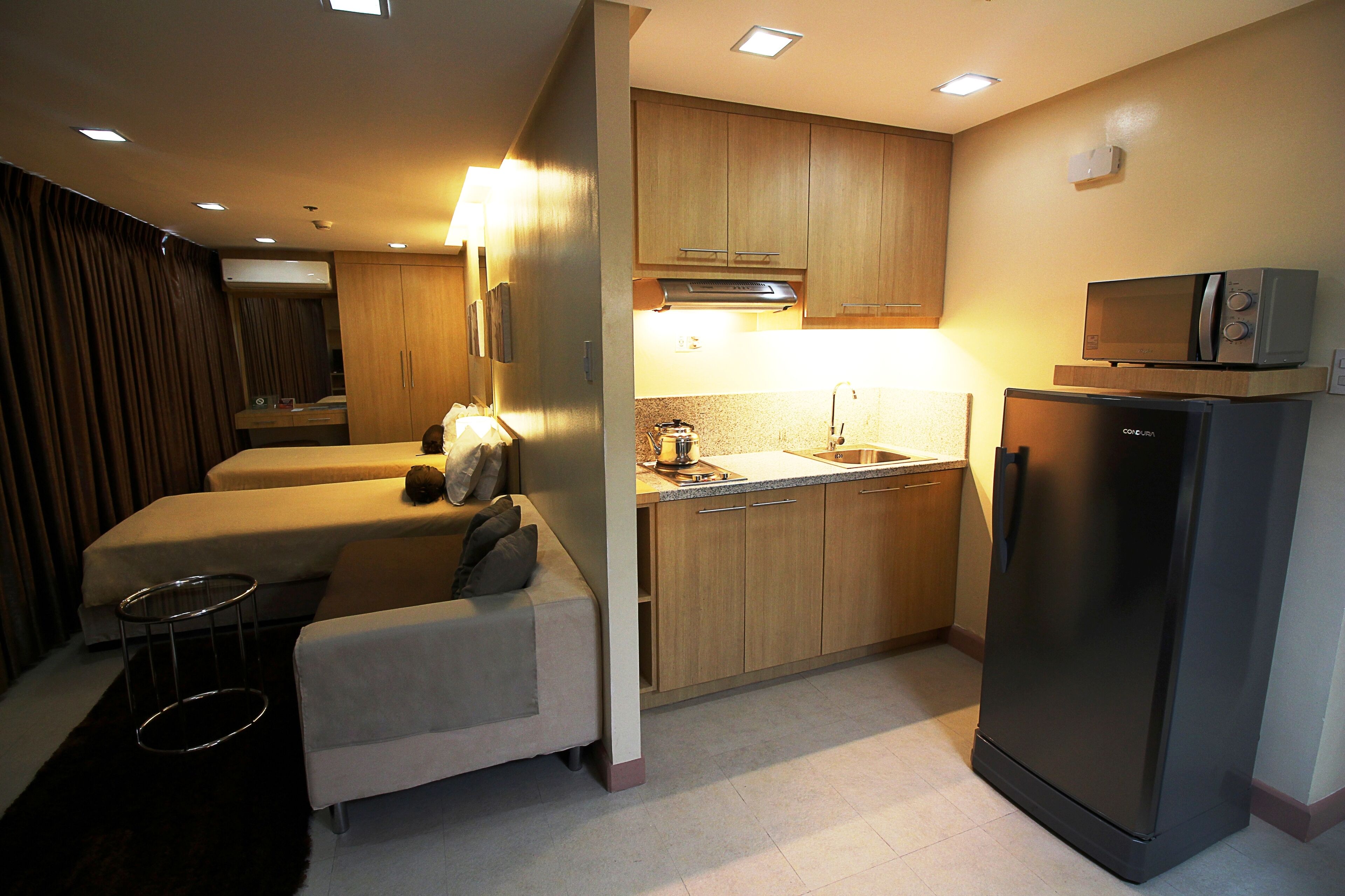 A compact kitchen with a refrigerator, microwave, and sink. There is a small dining area with a table and chairs.