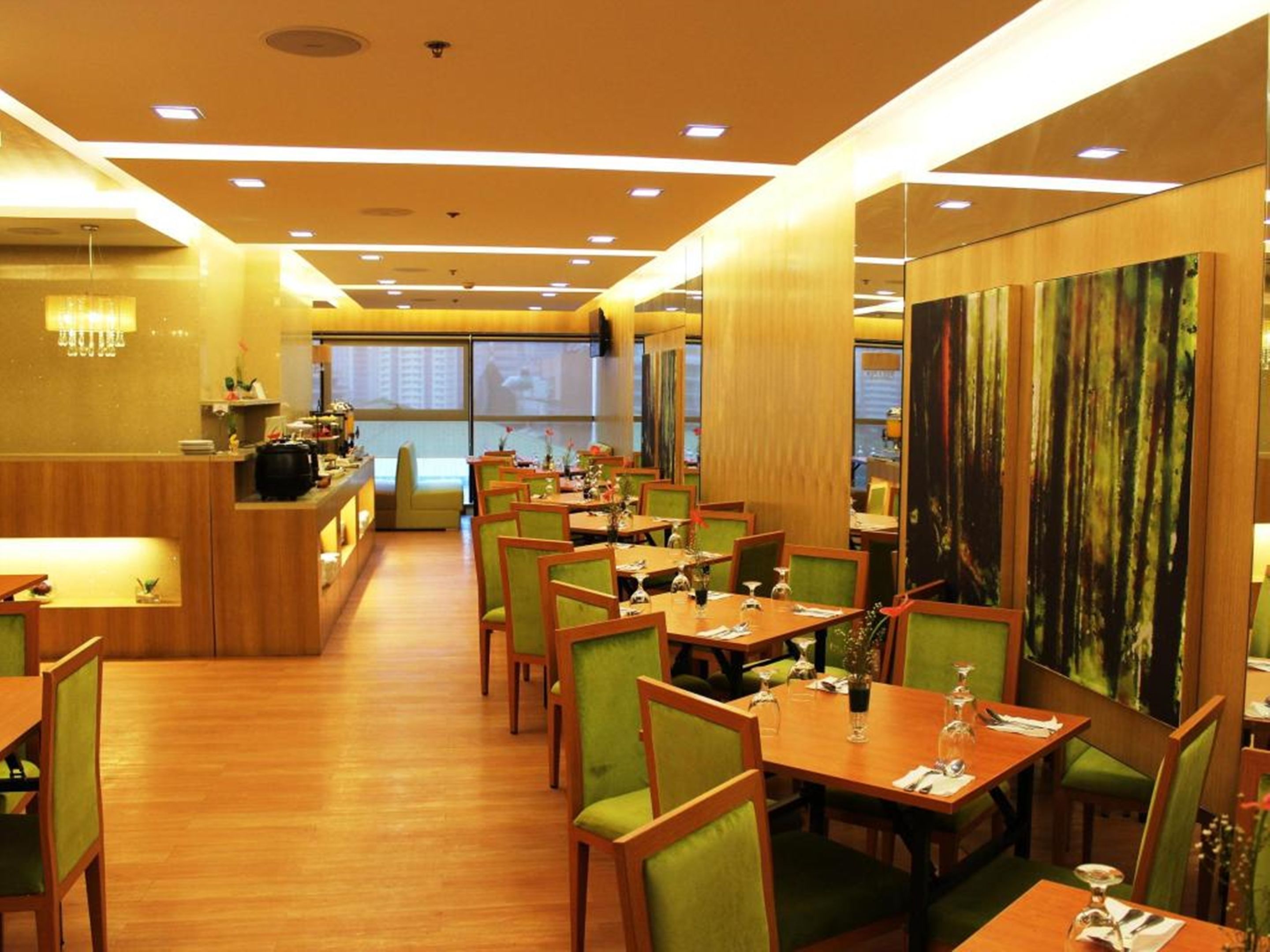 A restaurant with wooden tables and chairs, a counter with a menu, and a large painting on the wall.