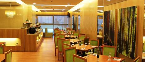 A restaurant with wooden tables and chairs, a counter with a menu, and a large painting on the wall.