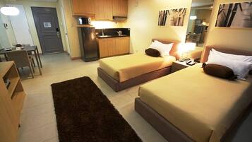 Une chambre d’hôtel avec deux lits, une kitchenette, un coin repas et un petit bureau.