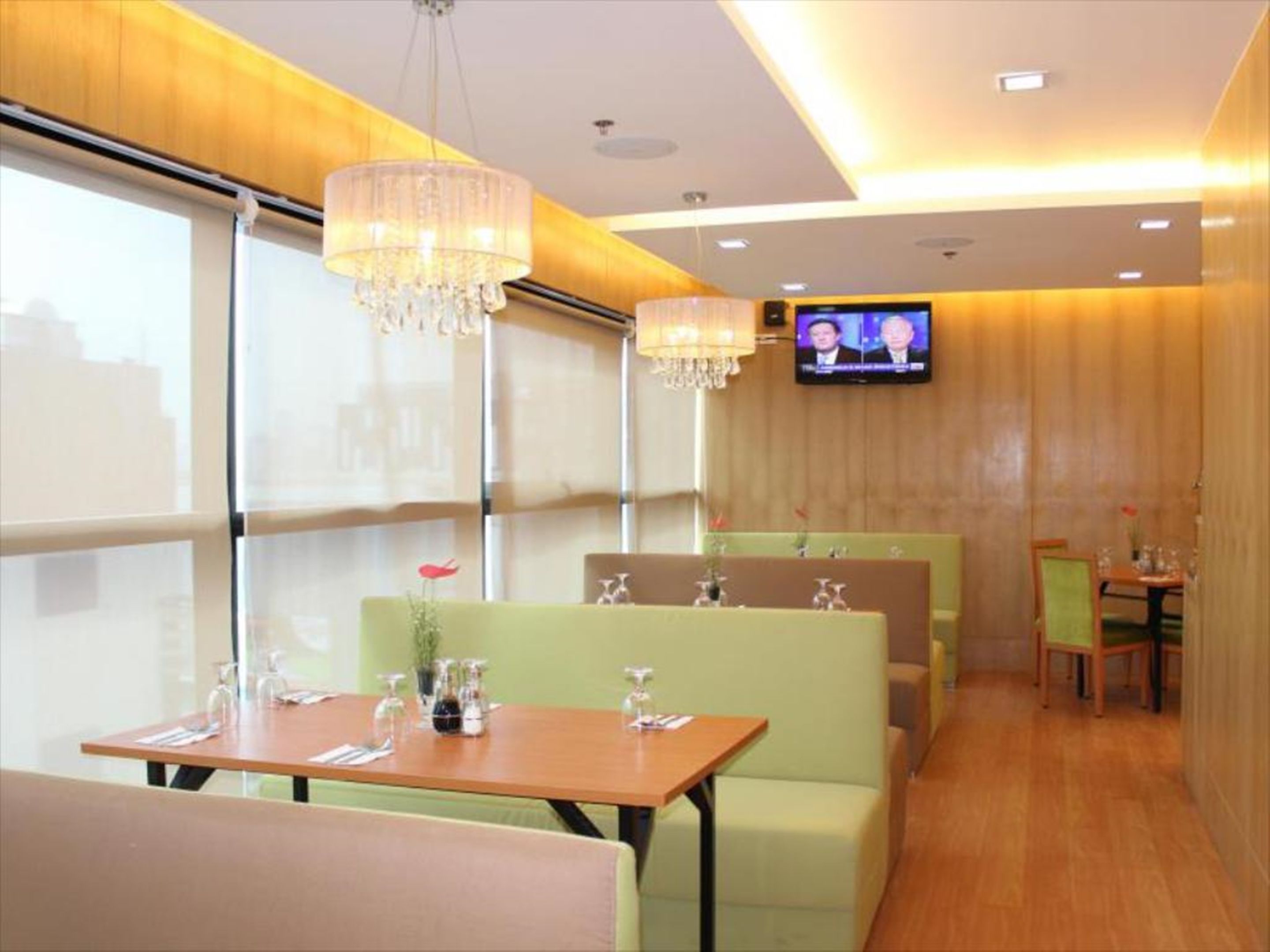 A restaurant with booths, tables, and a TV screen.