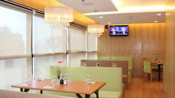 A restaurant with booths, tables, and a TV screen.