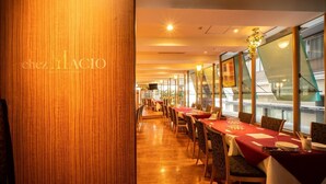 Un restaurant avec de longues tables, un plancher en bois et de grandes fenêtres.
