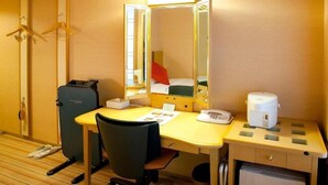 Une chambre d’hôtel équipée d’un bureau, d’une chaise, d’un miroir et d’un petit réfrigérateur.