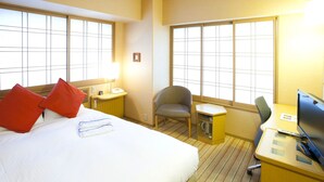 Une chambre d’hôtel avec un lit, un bureau, une chaise et de grandes fenêtres.