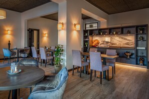 A modern dining area with round tables, cushioned chairs, and ambient lighting. - Hulsman (Valkenburg aan de Geul)