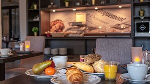 A breakfast setting with plates of pastries, fruits, and a glass of orange juice. - Hulsman (Valkenburg aan de Geul)