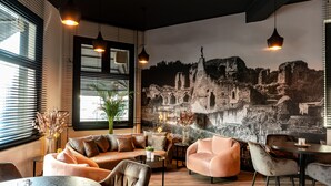 A modern interior with a large mural, leather sofas, and pendant lighting. - Hulsman (Valkenburg aan de Geul)