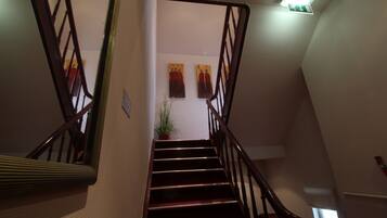 A staircase with wooden railings and a handrail, leading to an upper floor.