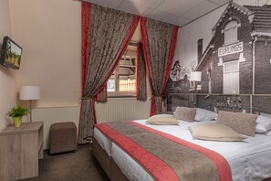 A bedroom with a bed, curtains, a radiator, a small table with a plant, and a wall mural. - Hulsman (Valkenburg aan de Geul)