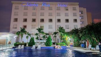 Un hotel con piscina, palmeras y sillas de descanso.