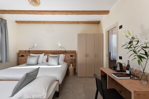 Une chambre à coucher avec une tête de lit en bois, deux lits, un bureau avec une chaise, une armoire et une table de chevet avec une lampe.