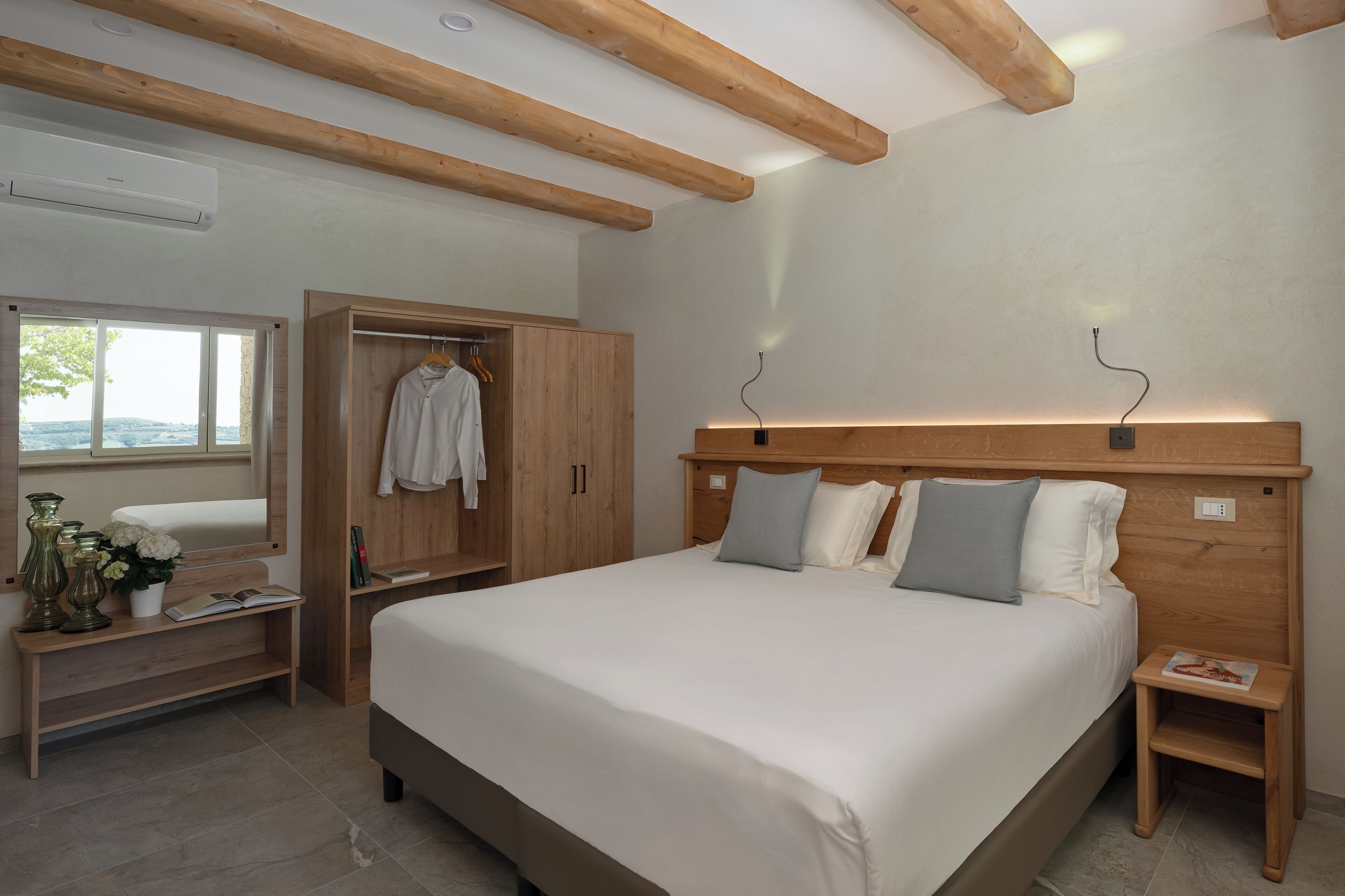 Ein Schlafzimmer mit einem großen Bett, einem Holzkopfende, Nachttischen, einem Kleiderschrank und einem Fenster mit Blick.