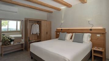 Ein Schlafzimmer mit einem großen Bett, einem Holzkopfende, Nachttischen, einem Kleiderschrank und einem Fenster mit Blick.