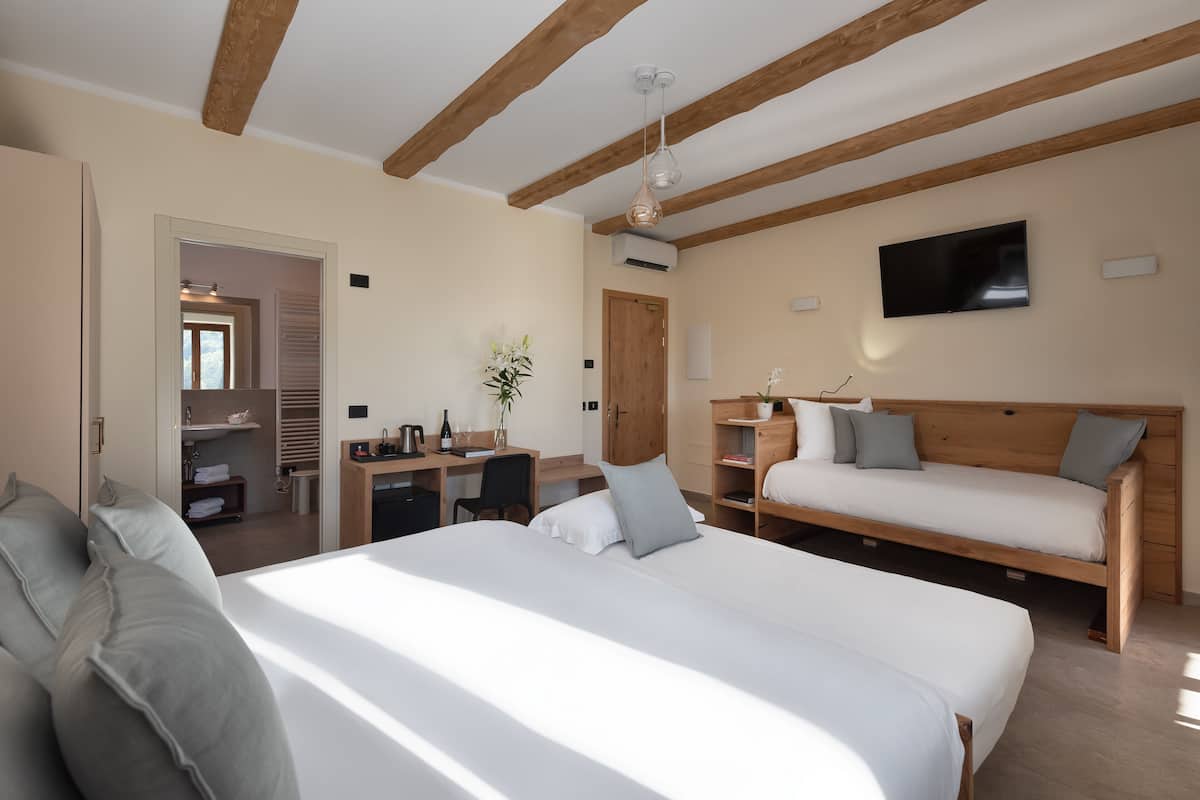 A modern hotel room with a large bed, a desk, a sofa, and a TV.