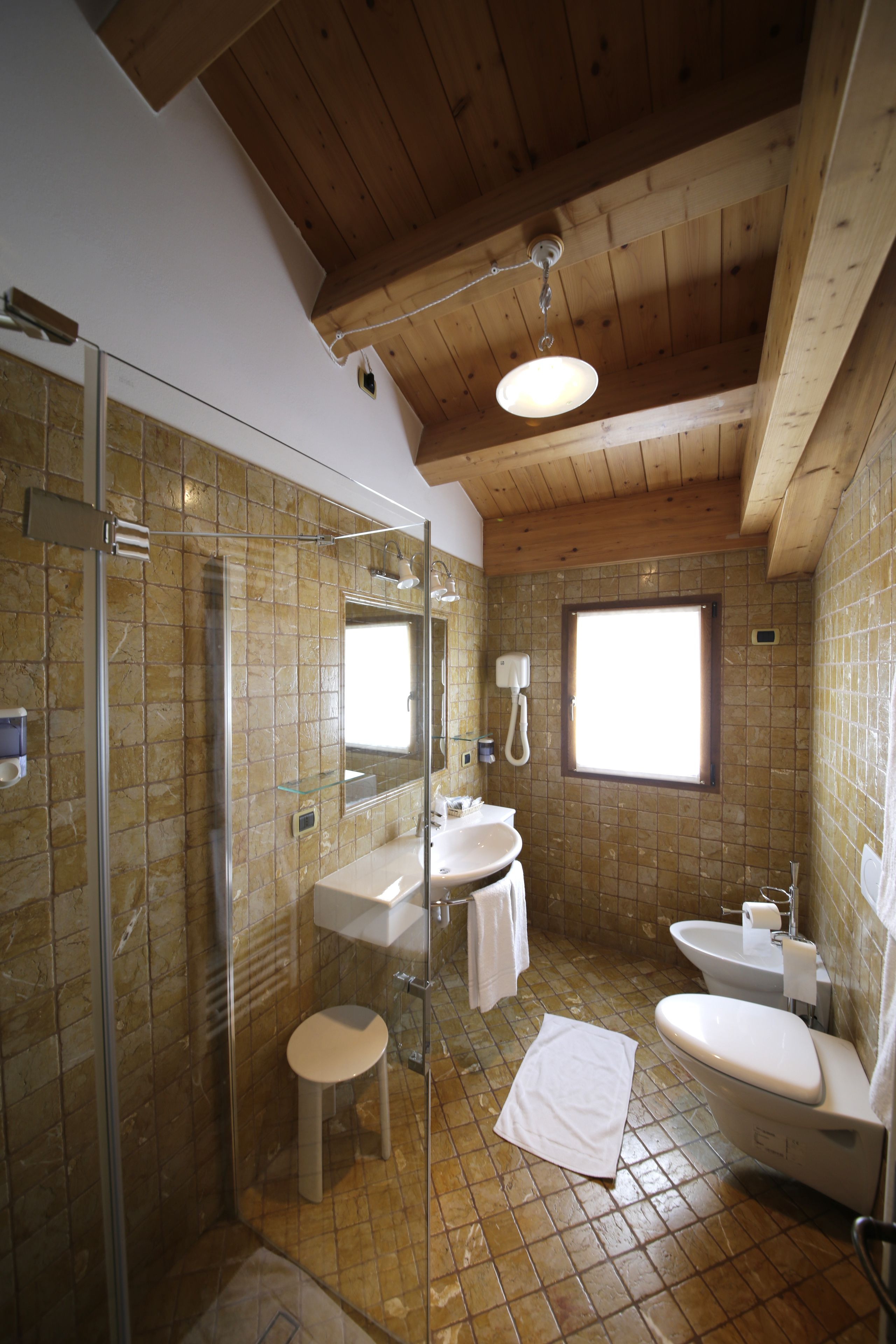 Een badkamer met een douchecabine van glas, een wastafel, een toilet en een raam.