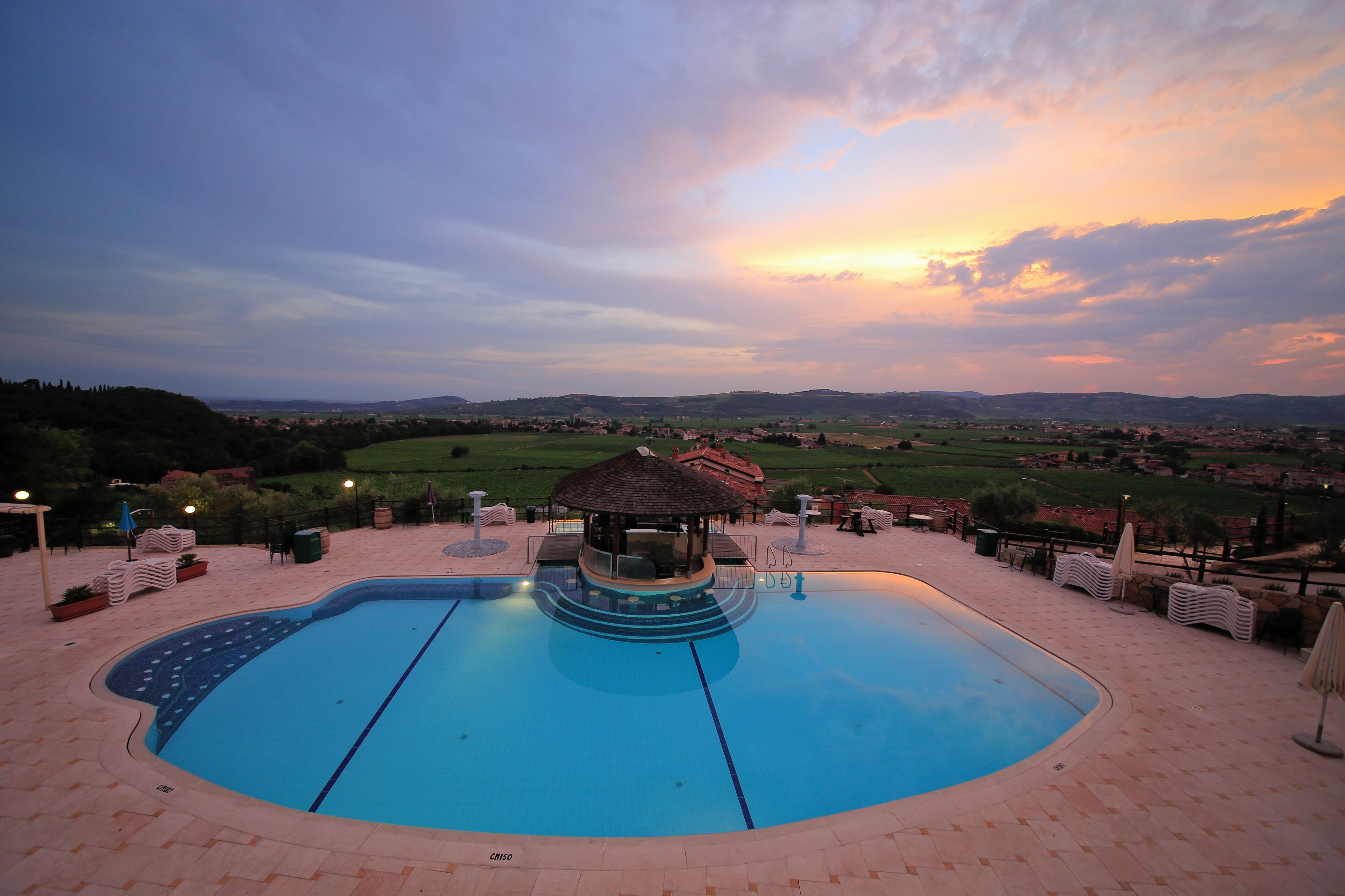A swimming pool with a gazebo, lounge chairs, and a view of the countryside.