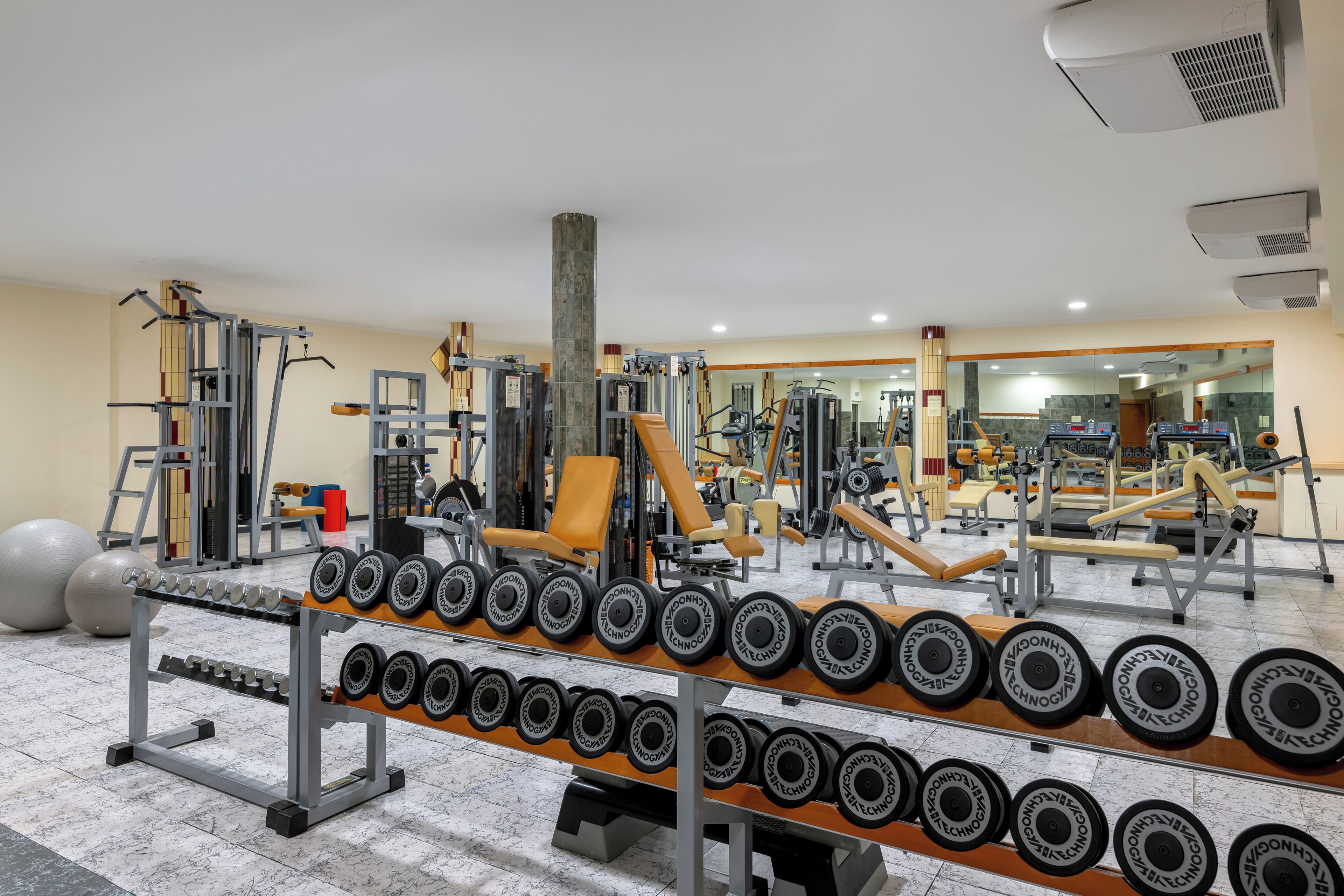 A gym with weightlifting equipment, dumbbells, and exercise machines.