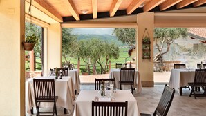 Ett utomhusområde med bord och stolar, utsikt över landskapet och ett tak av trä.
