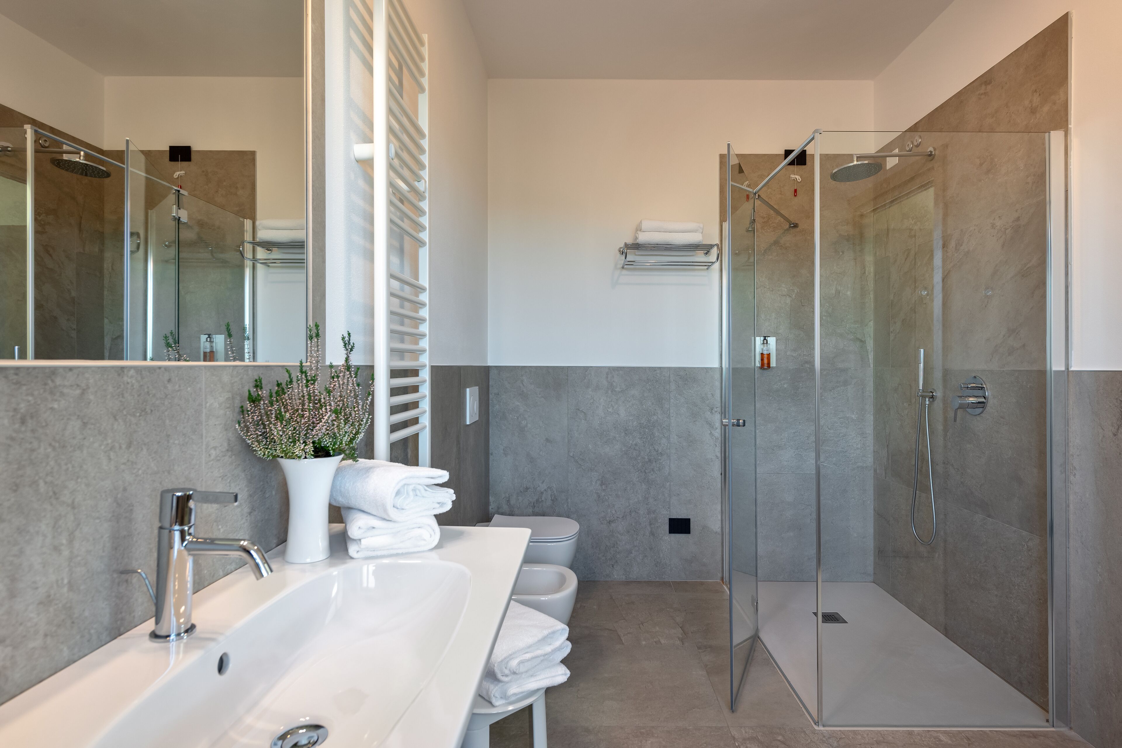 A modern bathroom with a large sink, a glass shower enclosure, and a toilet.