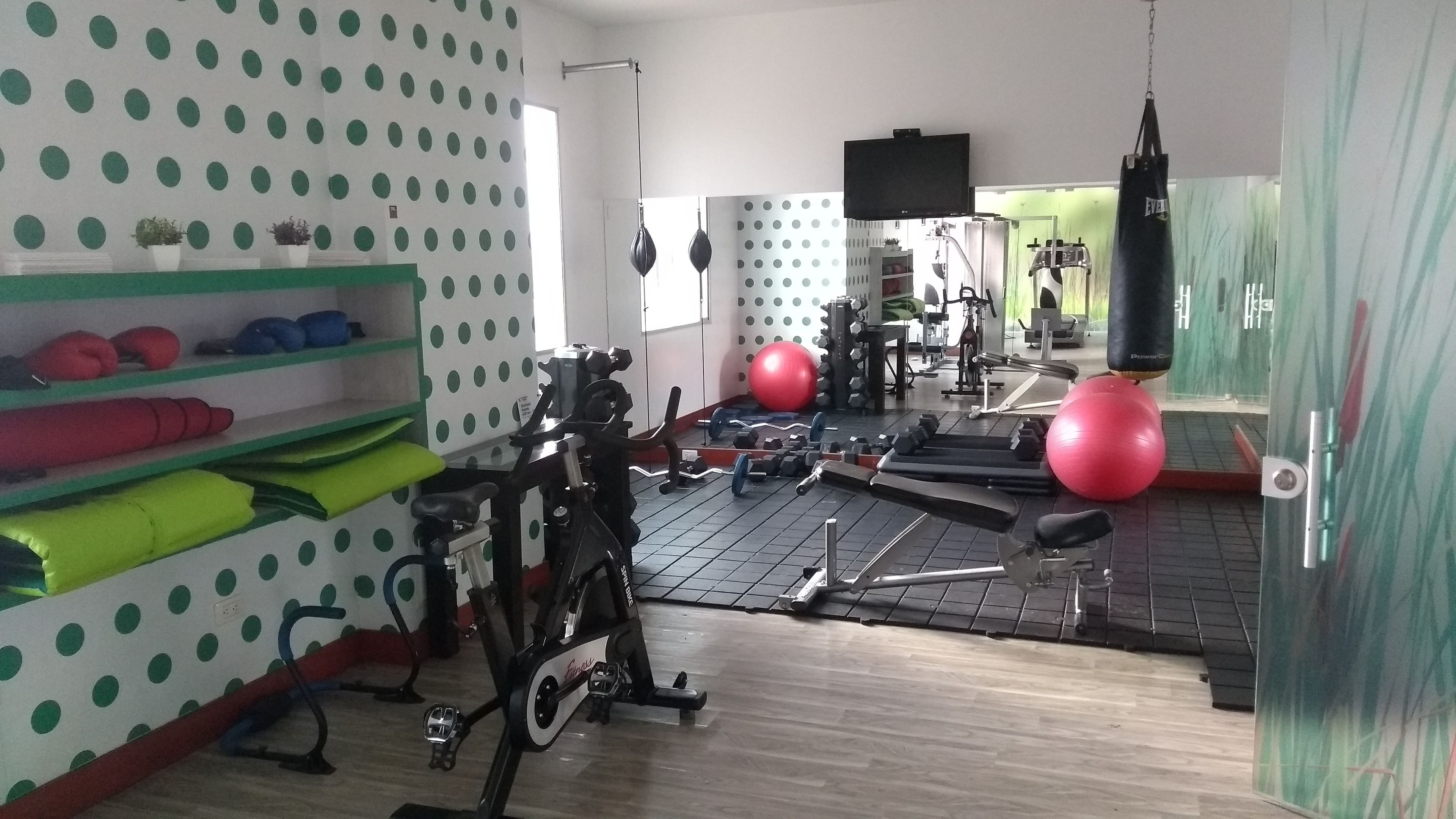 A gym with exercise equipment, a punching bag, and a mirror on the wall.