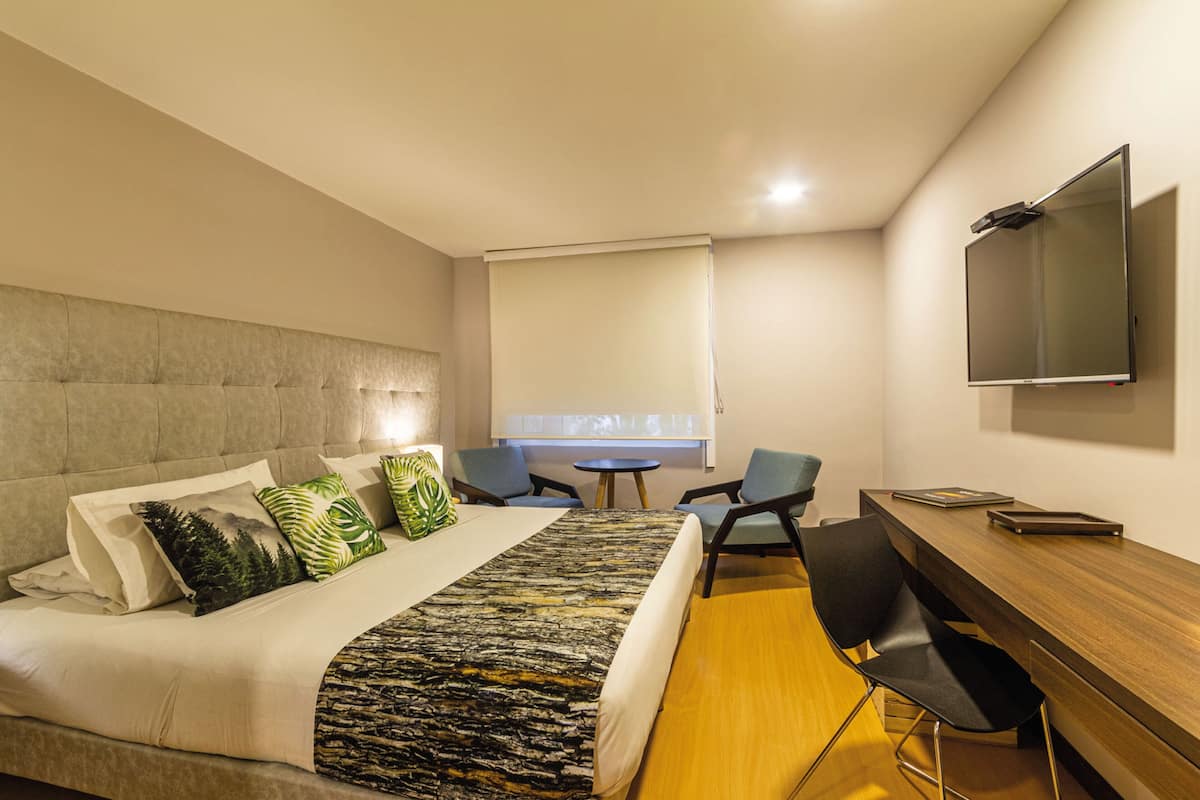 Une chambre d’hôtel moderne équipée d’un lit, d’un bureau, d’une chaise et d’un téléviseur.