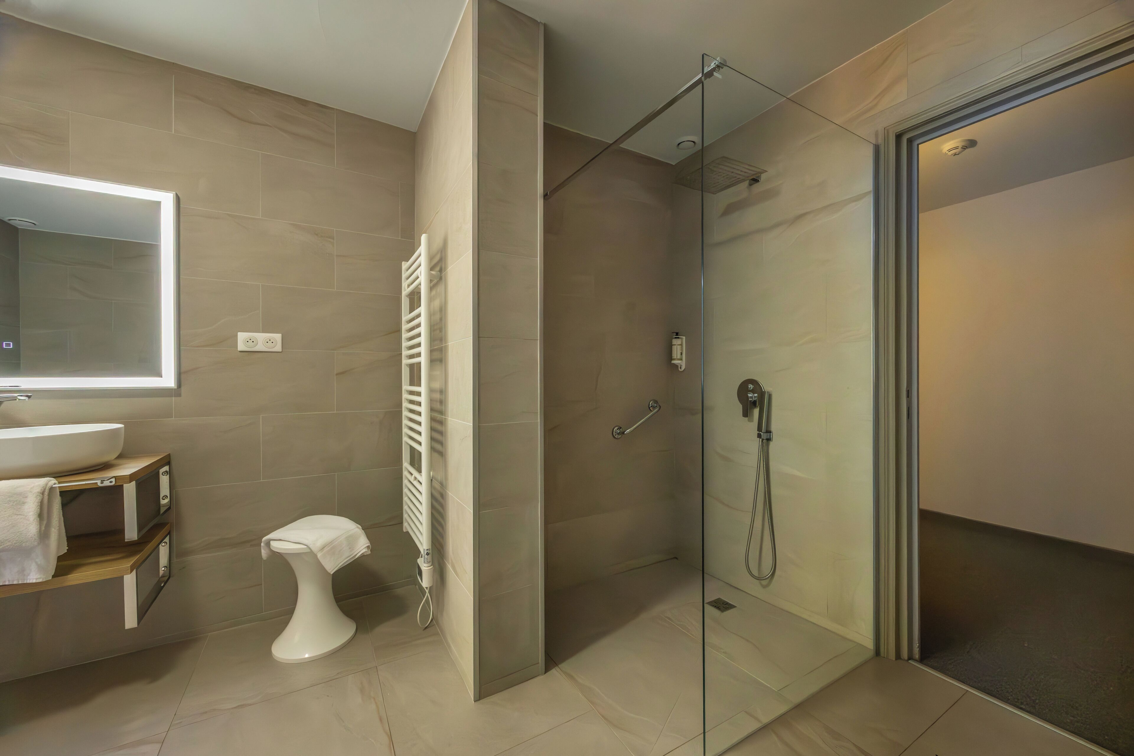 A modern bathroom with a glass-enclosed shower, a white toilet, and a large mirror.