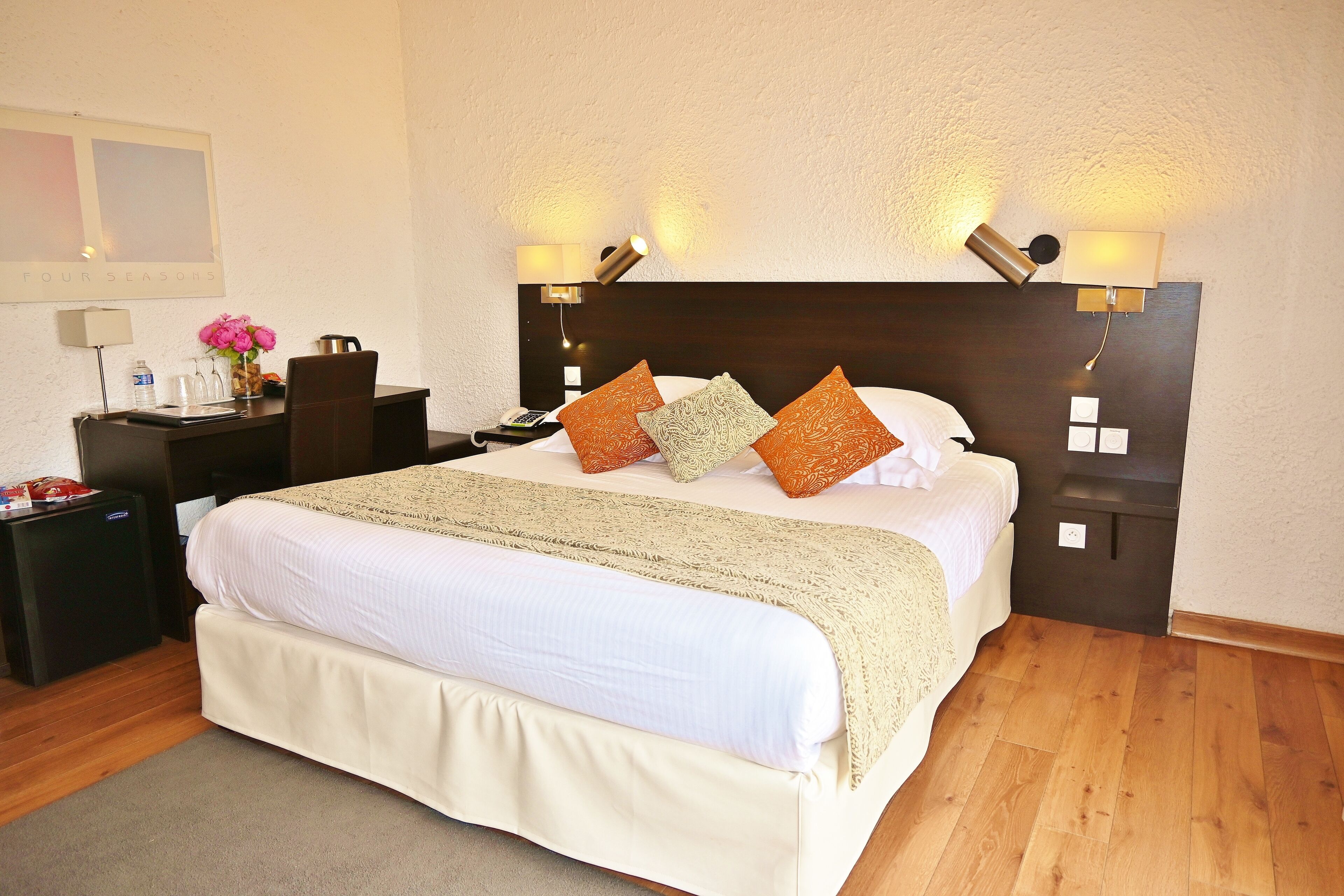 Een verzorgde hotelkamer met een groot bed, nachtkastjes, een bureau en een stoel.