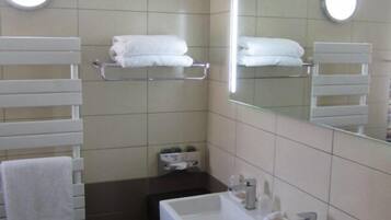 Un baño moderno con un lavamanos blanco, encimera oscura y dos toalleros con toallas blancas.