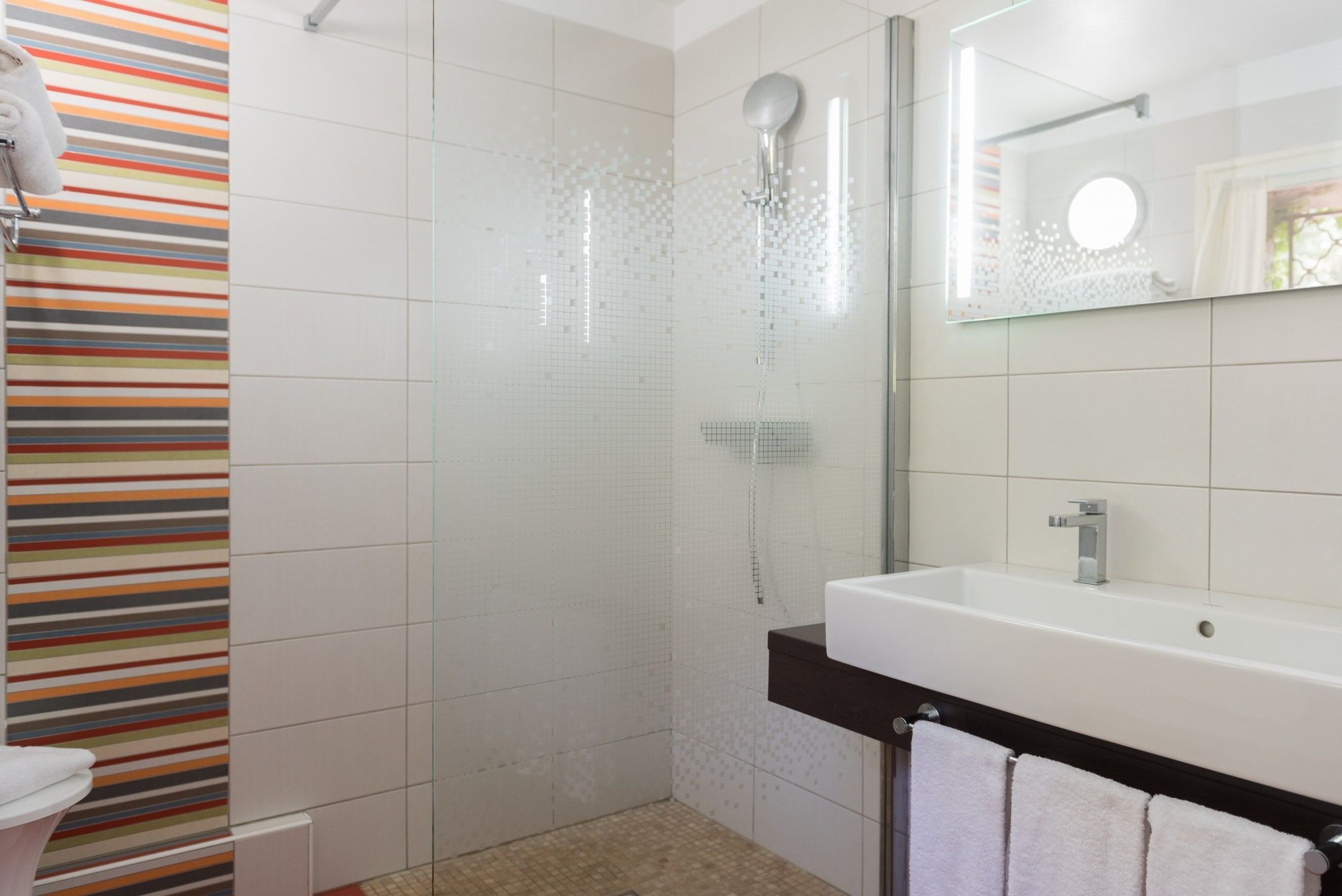 A modern bathroom with a shower, a sink, and a mirror.