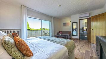 Een slaapkamer met een groot bed, een bank, een eettafel en uitzicht op de omgeving.