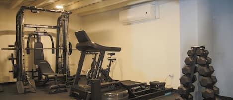A home gym with a treadmill, weight bench, dumbbells, and a stationary bike.