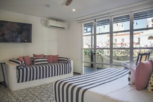 Un dormitorio con un ventanal grande, un sofá, una cama y un televisor.