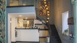 Un interior moderno con una zona de bar, una escalera y arte decorativo en la pared.