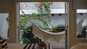 Una habitación con una hamaca, un sombrero y un libro sobre un cojín a rayas.