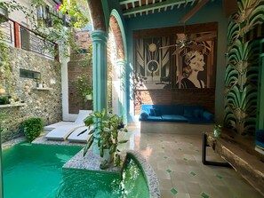 Un área de piscina con un muro de piedra, un sofá azul y un mural decorativo.