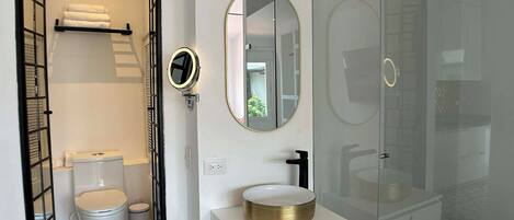 A modern bathroom with a toilet, sink, and mirror.