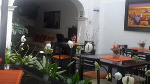Un comedor con mesas, sillas y plantas en macetas.
