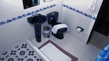Une salle de bain avec un lavabo, des toilettes et une étagère en verre au-dessus du lavabo, le tout de couleur noire.