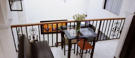 Un coin repas avec une table et des chaises, une rambarde noire et un tableau accroché au mur.
