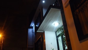 Un edificio moderno de noche con una entrada bien iluminada y una planta en maceta afuera.