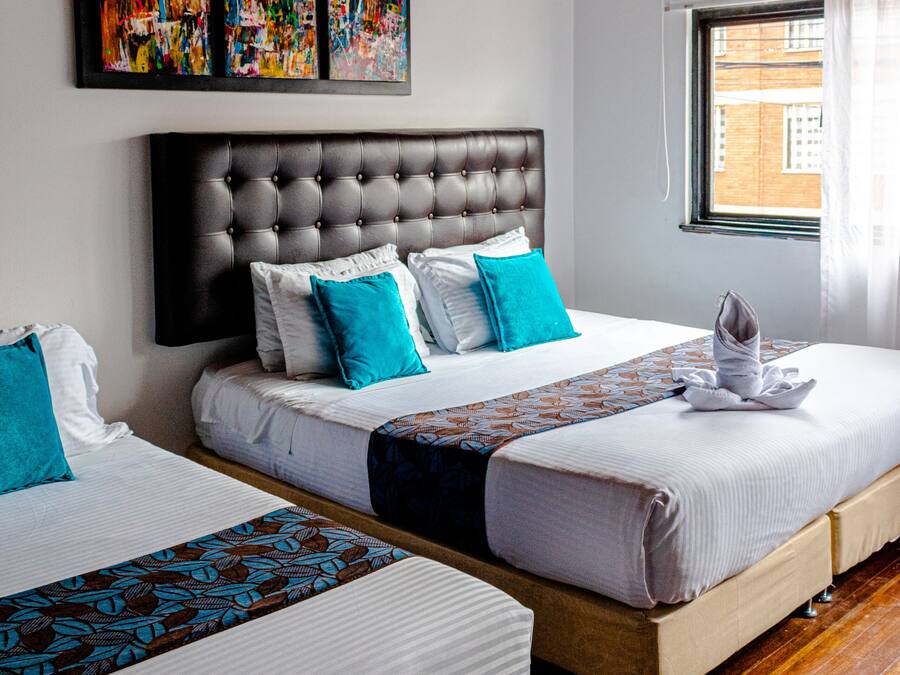 Habitación de hotel con dos camas, techo de madera y una obra de arte en la pared.