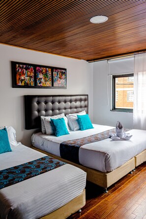 A hotel room with two beds, a wooden ceiling, and artwork on the wall.