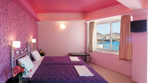 Quarto com duas camas, televisão e varanda vista para o mar.