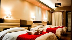Habitación de hotel con dos camas, un sofá y una manta roja.
