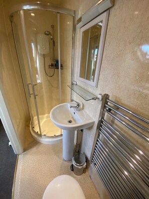A bathroom with a glass shower enclosure, a pedestal sink, a toilet, and a towel rack. - Autumn Leaves Guest House (Windermere)