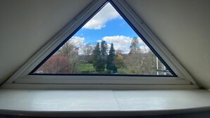 Un tragaluz triangular con vistas a árboles y un cielo despejado.